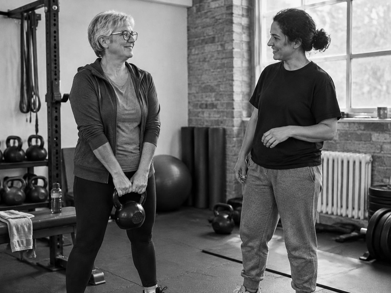 Client learning a light kettlebell hinge while her coach gives a friendly cue
